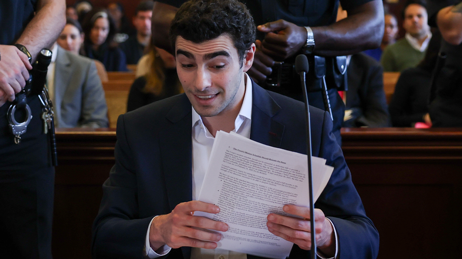Luigi Mangione holds papers in court during a hearing.