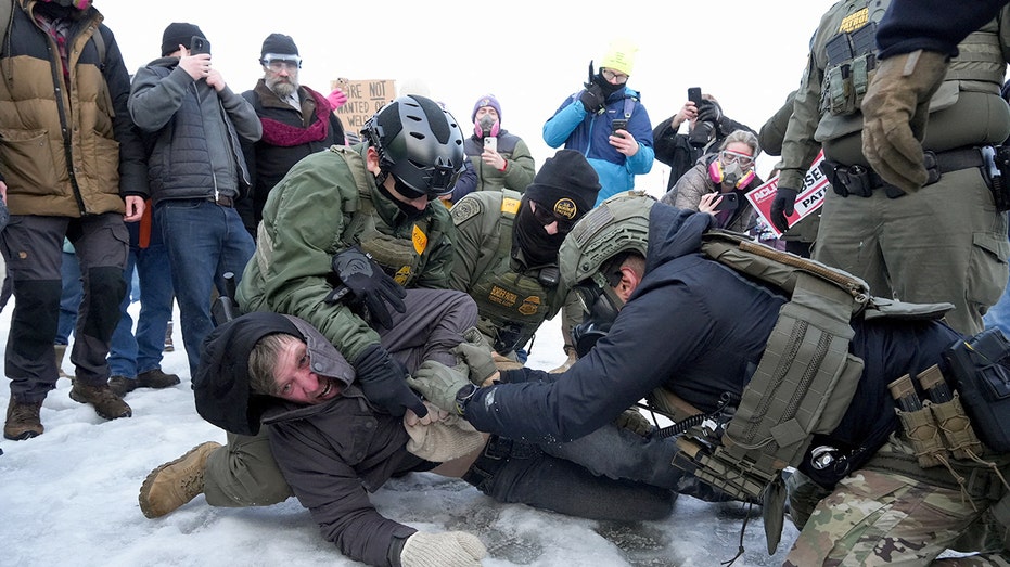 Protesters in Minneapolis near DHS officers following a fatal ICE shooting; Minnesota National Guard on standby.