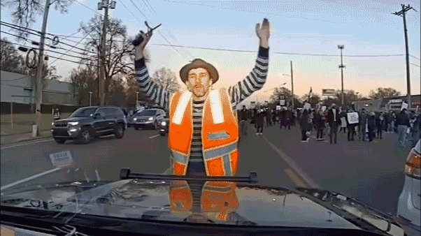 Animated dashcam clip from a Tennessee Highway Patrol vehicle showing a man in an orange safety vest stepping in front of the patrol car during a Memphis protest.